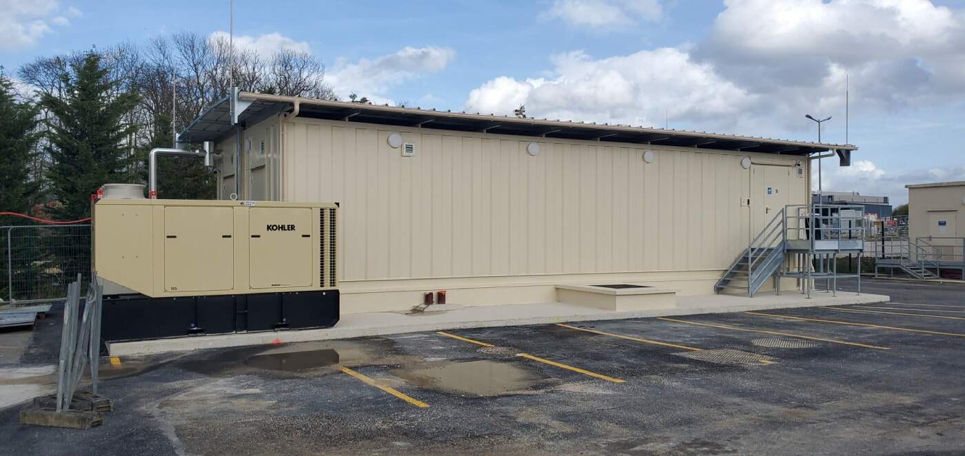 Bâtiment technique modulaire équipé d’un groupe électrogène et d’installations électriques sur un site industriel.