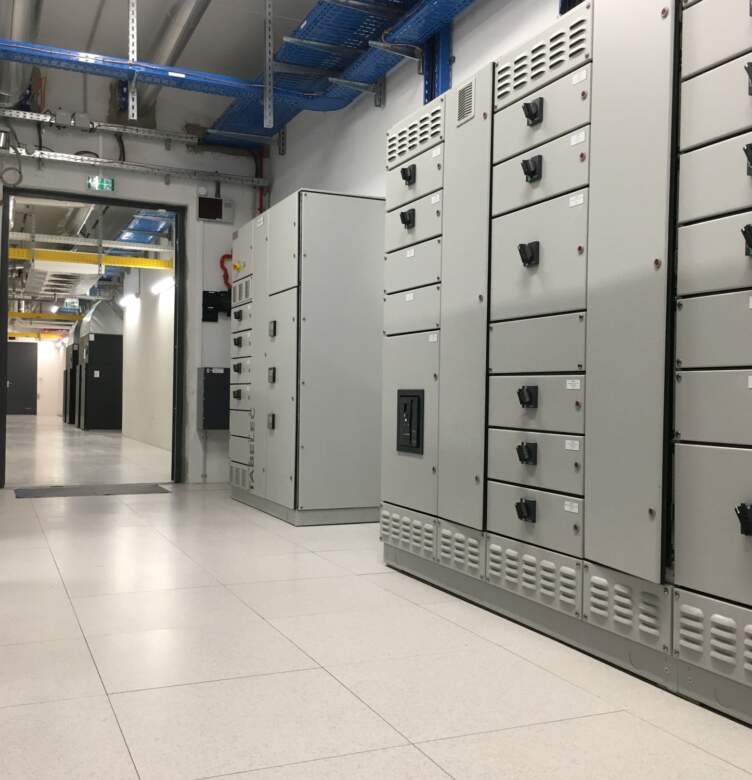 Local électrique avec armoires de distribution, tableaux basse tension et chemins de câbles dans un environnement technique.