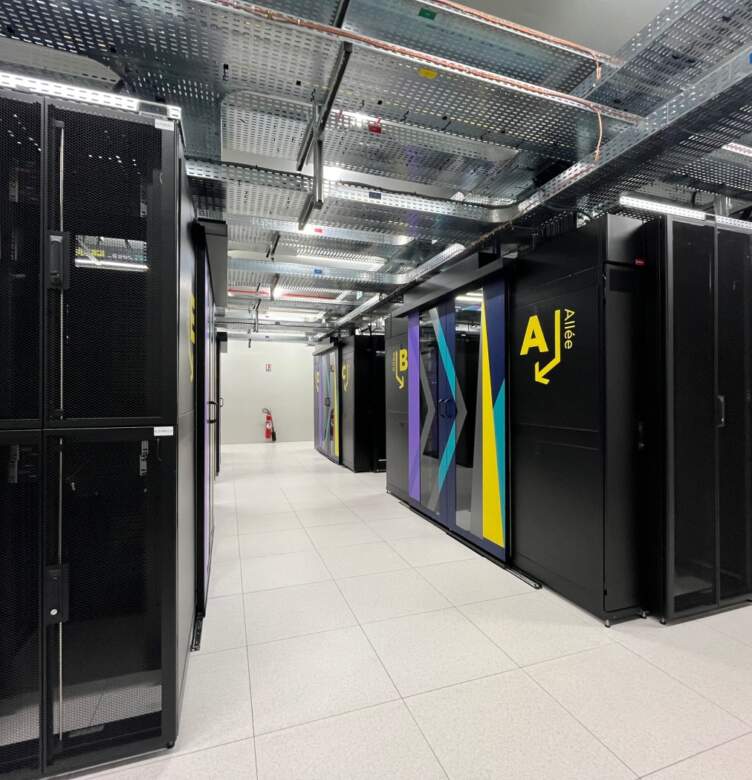Allée de data center avec baies serveurs, armoires informatiques et chemins de câbles en plafond.