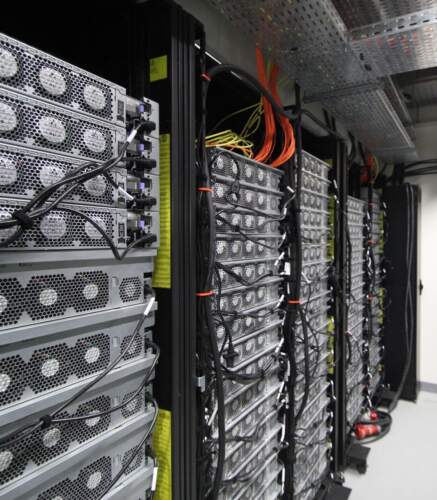 Racks de serveurs informatiques avec équipements réseau et câblage dans une salle informatique.