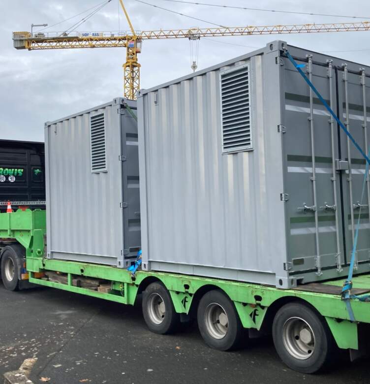 Transport de conteneurs techniques modulaires sur un camion plateau vers un site industriel.