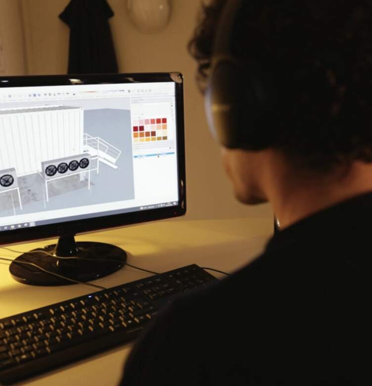 Technicien travaillant sur un ordinateur avec un logiciel de modélisation 3D pour concevoir une installation technique industrielle.