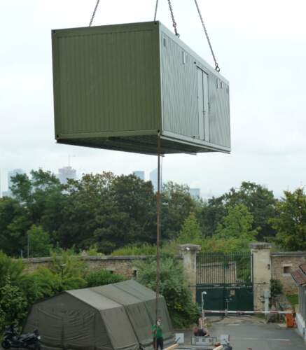 Module technique préfabriqué en cours de levage par une grue pour installation sur site.