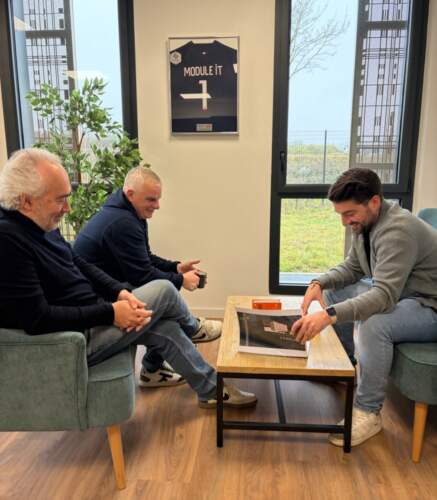 Échange entre collaborateurs autour d’une table lors d’une discussion de projet dans un bureau.