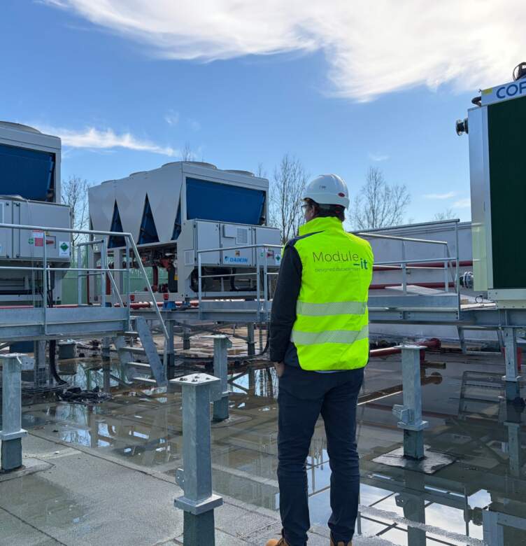 Technicien sur site inspectant des équipements de refroidissement installés sur une plateforme technique extérieure.