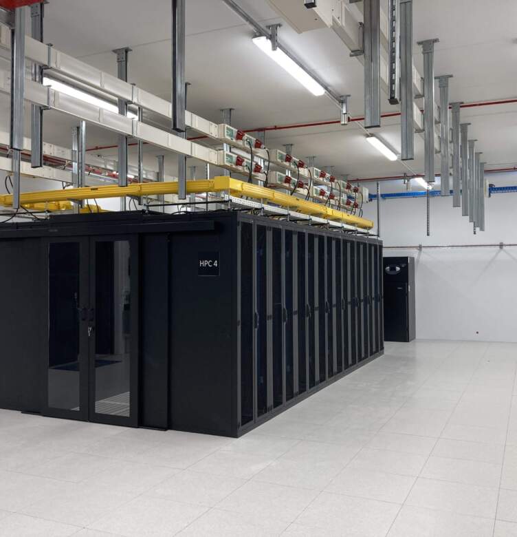 Salle de serveurs avec une rangée de cabinets noirs, éclairage lumineux, câbles jaunes en hauteur et sol en carrelage blanc.