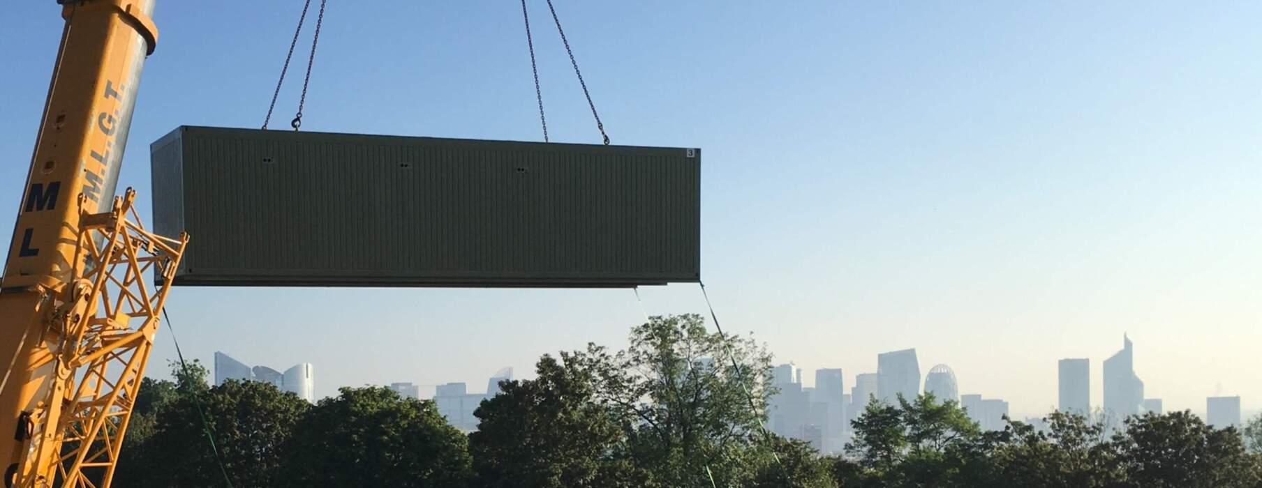 Vue aérienne d’une installation technique comprenant un container central, plusieurs groupes de refroidissement et un réseau de conduites métalliques, le tout dans une enceinte sécurisée.