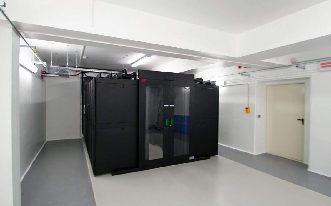 A modern room with black server cabinets. Light-colored concrete floors, gray walls, and LED ceiling lighting.