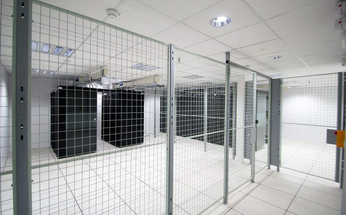 Salle de serveurs à l'Université de Nantes, avec des armoires noires encadrées par des grilles métalliques dans un environnement lumineux.