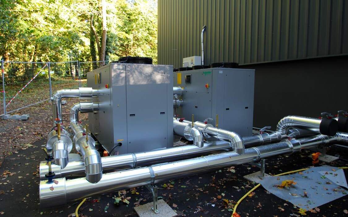 Systèmes de chauffage avec conduits en métal, installés à l'extérieur, entourés d'arbres dans un environnement naturel.